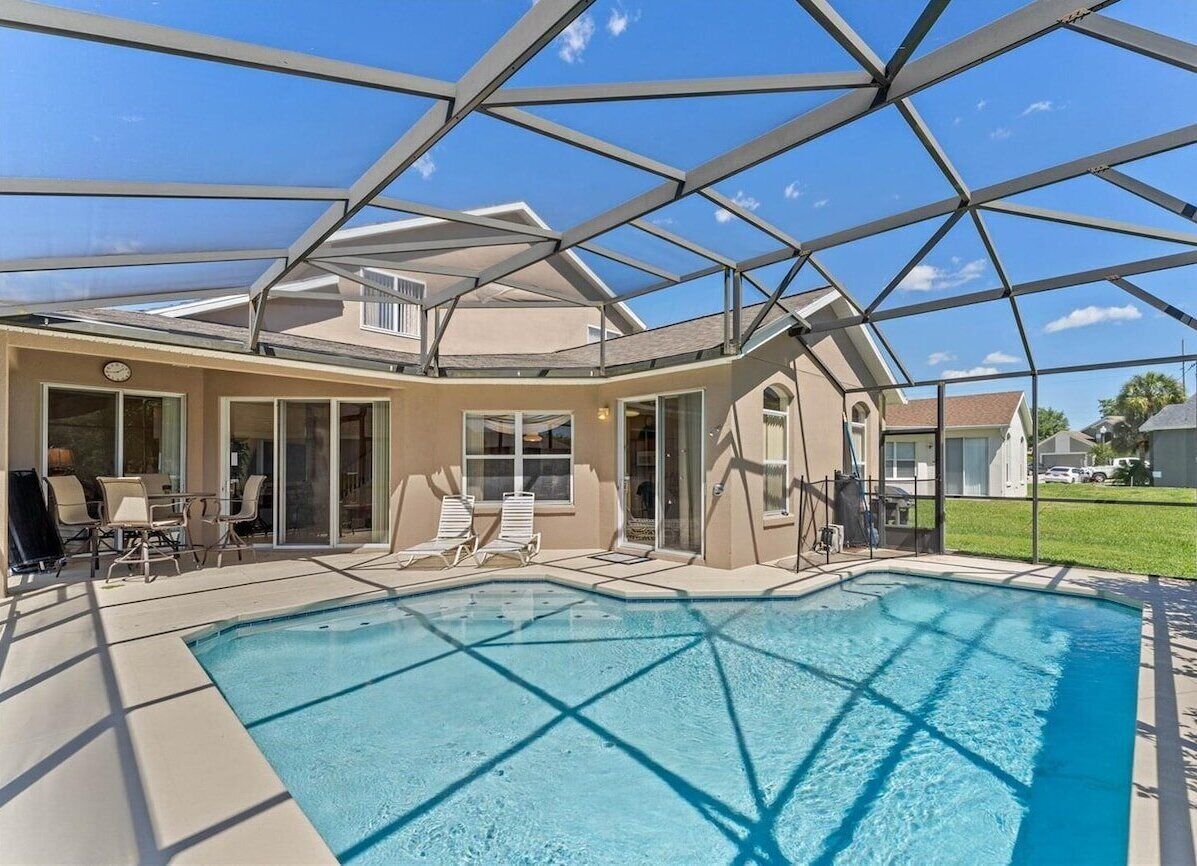 Ein Schwimmbad mit Glasdach, Liegestühlen und einer Terrassenanlage.