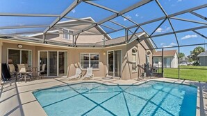 A swimming pool with a glass ceiling, lounge chairs, and a patio area. - 229 Corvina Drive Davenport, 5bed (Davenport)