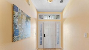 A hallway with a white door, a large abstract painting on the wall, and a light fixture on the ceiling. - 229 Corvina Drive Davenport, 5bed (Davenport)