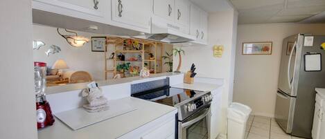 Une cuisine moderne avec des meubles blancs, une cuisinière et un réfrigérateur.