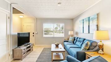 A living room with a TV, sofa, coffee table, and artwork on the wall.