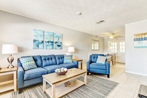 A modern living room with a blue sofa, a wooden coffee table, and a dining area in the background. - 2810 Ohio Avenue #1 (Fernandina Beach)