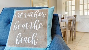 A blue sofa with a pillow that reads "I'd rather be at the beach." - 2810 Ohio Avenue #1 (Fernandina Beach)