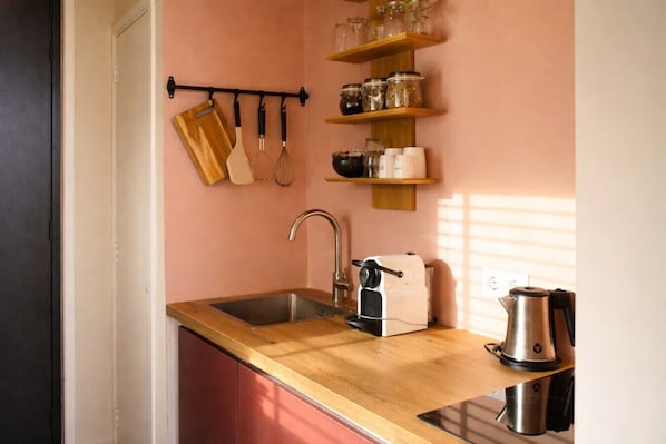 A kitchen with a wooden countertop, stainless steel sink, and a coffee maker.