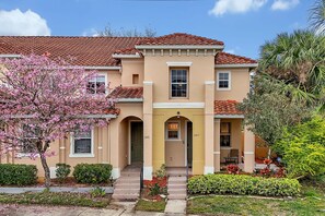 A two-story building with a red-tiled roof, a central entrance with a small porch, and numbered doors. - 2663 Andros Lane, Kissimmee, 3 BED (Kissimmee)