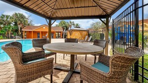 An outdoor patio with wicker furniture, a pool, and a covered area with a view of the pool and surrounding buildings. - 2663 Andros Lane, Kissimmee, 3 BED (Kissimmee)