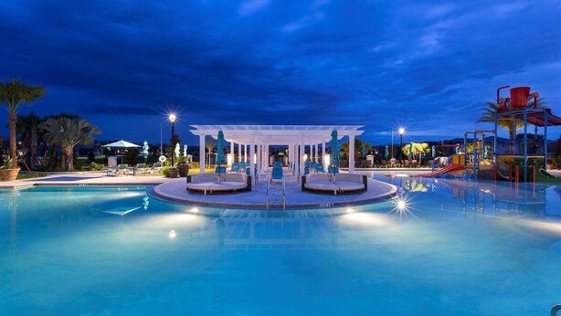 A swimming pool with a central pavilion, lounge chairs, and a water slide. - 2440-5-td-perfect Villa at Windsor (Kissimmee)