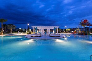 A swimming pool with a central pavilion, lounge chairs, and a water slide. - 2440-5-td-perfect Villa at Windsor (Kissimmee)