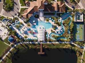 An aerial view of a resort with a large swimming pool, a tennis court, and a dock over water. - 2440-5-td-perfect Villa at Windsor (Kissimmee)