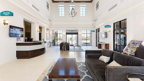 A spacious lobby with a reception desk, a comfortable seating area, and a large chandelier. - 2440-5-td-perfect Villa at Windsor (Kissimmee)
