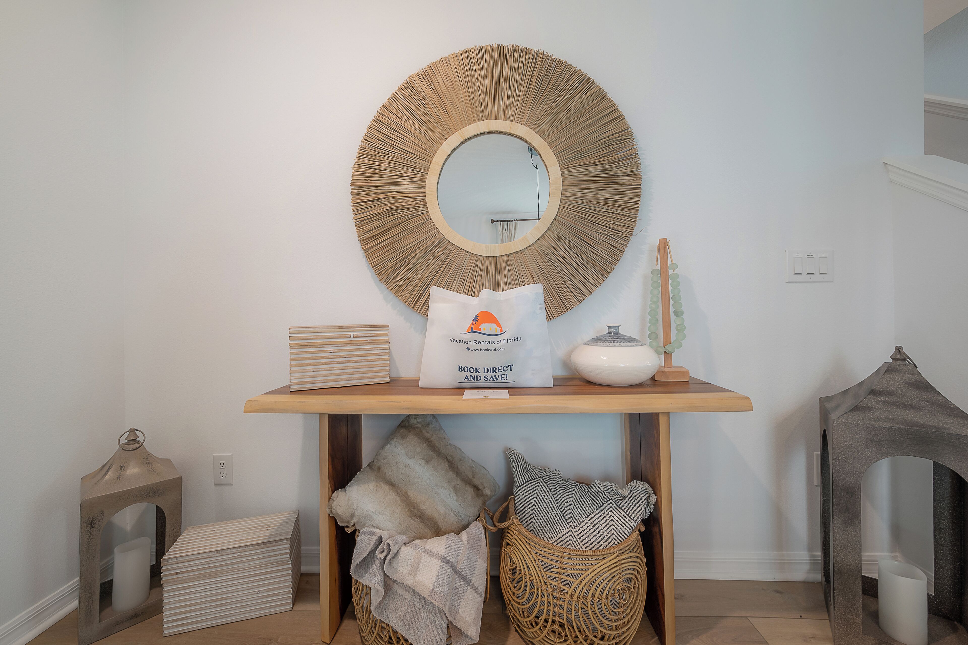 Une console en bois surmontée d’un miroir rond, avec un sac blanc et des objets décoratifs.