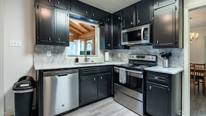 A modern kitchen with dark cabinets, stainless steel appliances, and a marble countertop. - 2431 Weatherford Court, Marietta (Marietta)
