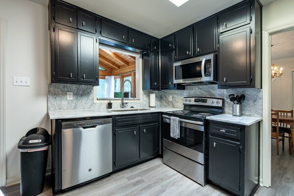 A modern kitchen with dark cabinets, stainless steel appliances, and a marble countertop. - 2431 Weatherford Court, Marietta (Marietta)