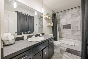 A modern bathroom with a large mirror, two sinks, a toilet, and a shower area. - 2431 Weatherford Court, Marietta (Marietta)