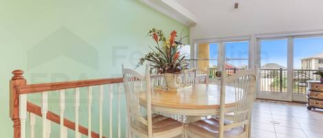 A dining area with a round table, white chairs, and a wooden railing.