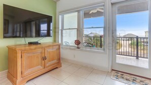 A room with a wooden cabinet, a flat-screen TV, large windows, and a balcony with a view. - 241 S Fletcher Ave (Fernandina Beach)