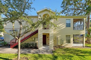 A two-story building with a red staircase, a balcony, and a front door. - 2728 Club Cortile Circle Unit A 3bed (Kissimmee)