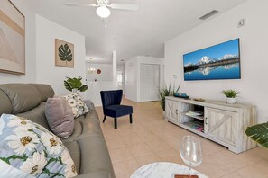 Una sala de estar con sofá, sillón, mesa de centro y televisor.