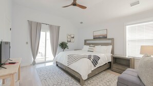 A modern bedroom with a bed, bedside tables, a TV, and a ceiling fan. - 26 N Washington Ave (Ventnor City)