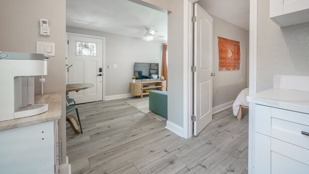 Eine moderne Küche mit integrierter Kaffeemaschine, ein Essbereich mit Tisch und Stühlen sowie ein Wohnzimmer mit Fernseher und einer kleinen Couch.
