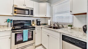 A modern kitchen with white cabinets, a stainless steel microwave, a black stove, and a dishwasher.