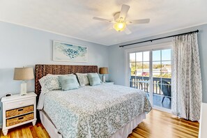Una camera da letto con un letto, comodini, una ventola a soffitto, una finestra con tende e vista sull'esterno.