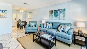 A living room with a sofa, coffee table, and a dining area with chairs and a table.