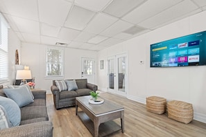 A modern living room with a large flat-screen TV mounted on the wall, a sofa, a coffee table, and a small side table with a plant. - 277 Milam Bridge Rd SW, Cartersville (Cartersville)