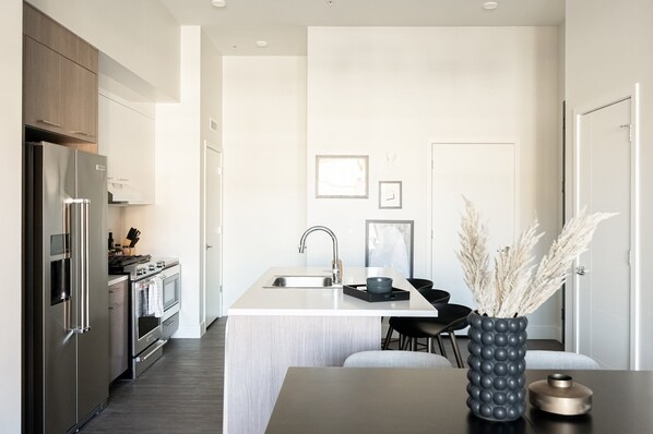 A modern kitchen with a central island, stainless steel appliances, and a minimalist design. - 2880: Relaxed Elegance at Espadin (Denver)
