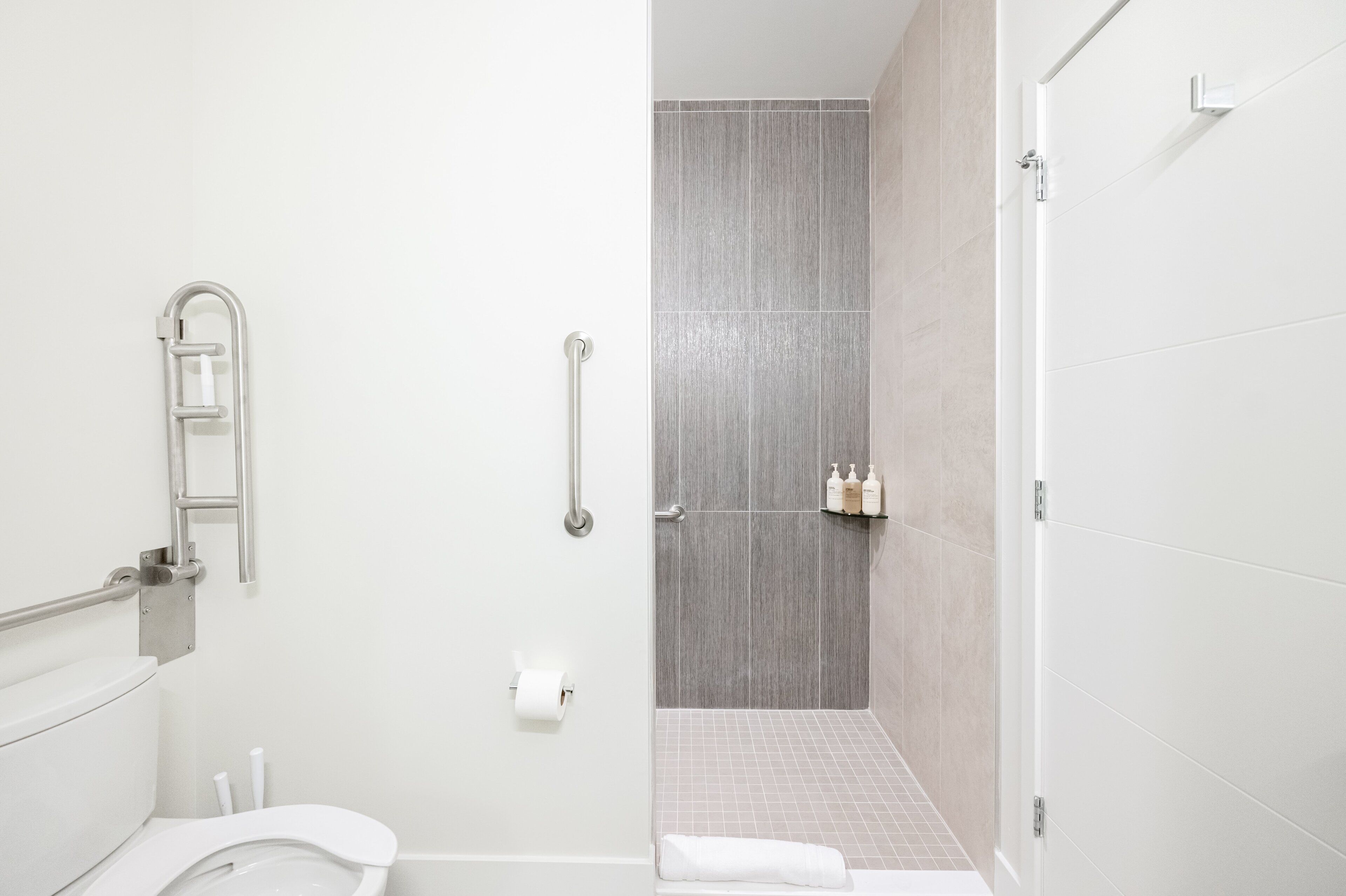 A modern bathroom with a toilet, a shower with a glass door, and a towel rack.