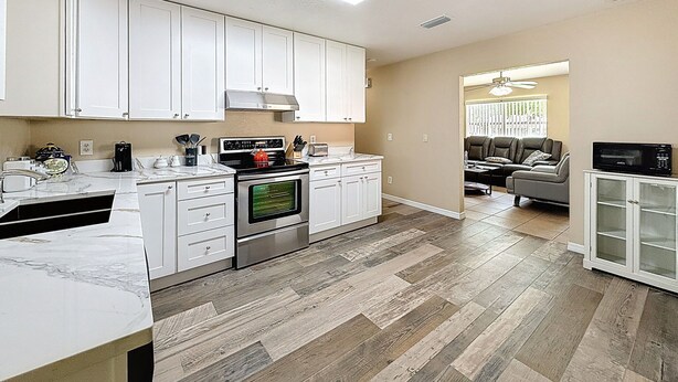 A modern kitchen with white cabinets, a built-in oven, and a microwave. - 2737 Bel Aire Circle (Tampa)