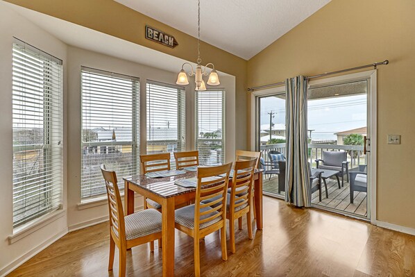 A dining area with a wooden table and chairs, large windows with blinds, and a view of the outdoors. - 2641a S Fletcher Ave (Fernandina Beach)
