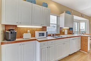 A kitchen with white cabinets, a microwave, a toaster, and a coffee maker. - 2641a S Fletcher Ave (Fernandina Beach)