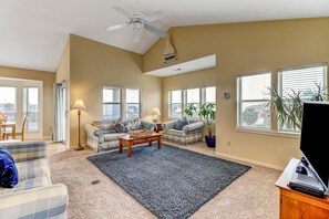 A spacious living room with a large ceiling fan, two couches, a coffee table, and a TV on a wooden stand. - 2641a S Fletcher Ave (Fernandina Beach)