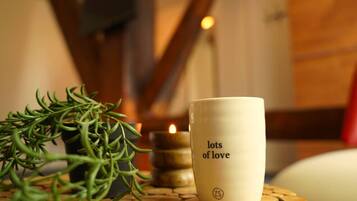 A candle, a mug with "lots of love" text, and a sprig of rosemary on a round table.