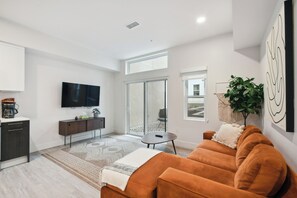 A modern living room with a large TV, a sofa, a coffee machine, and a plant. - 2880: Natural Influence Sanctuary at Espadin (Denver)