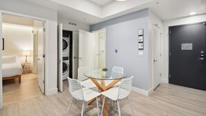 A modern hotel room with a glass dining table, white chairs, a black door, and a laundry area. - 2880: Natural Influence Sanctuary at Espadin (Denver)
