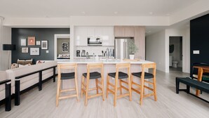 A modern kitchen with white cabinets, stainless steel appliances, and a central island with bar stools. - 2880: Rhythm of the Night Loft at Espadin (Denver)