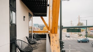 A balcony with black metal chairs and a view of a street with cars and a green sign. - 2880: Rhythm of the Night Loft at Espadin (Denver)