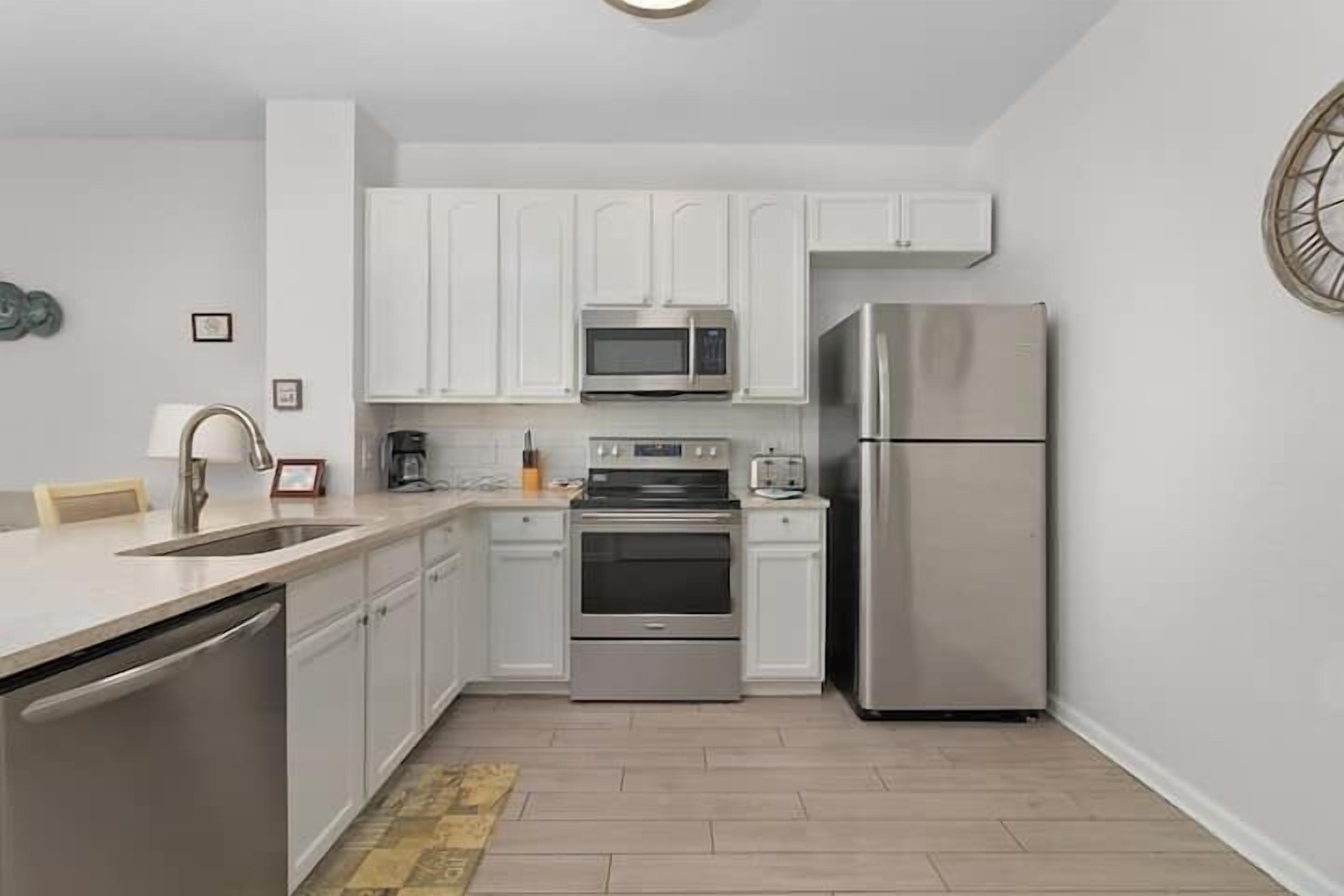 A modern kitchen with white cabinets, stainless steel appliances, and a dishwasher.