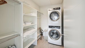 Une buanderie équipée d’un lave-linge à chargement frontal, d’un sèche-linge et d’une étagère où sont pliées les serviettes.