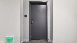 Une porte de couleur sombre, dotée d’un clavier numérique et d’un panneau indiquant la sortie.