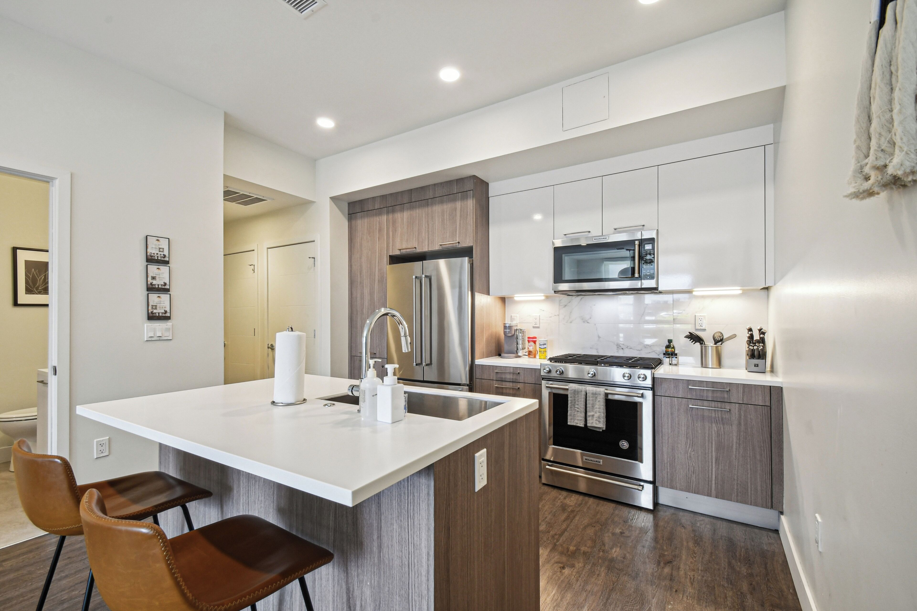 A modern kitchen with a central island, stainless steel appliances, and wooden cabinetry.