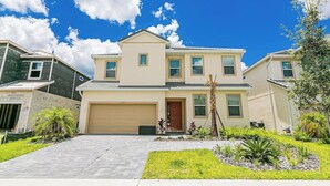 A two-story house with a garage, a well-maintained lawn, and a clear blue sky. - 2476 Shanti Drive 12bed (Kissimmee)