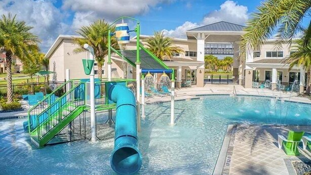 A swimming pool with a water slide and a covered area with chairs. - 2476 Shanti Drive 12bed (Kissimmee)