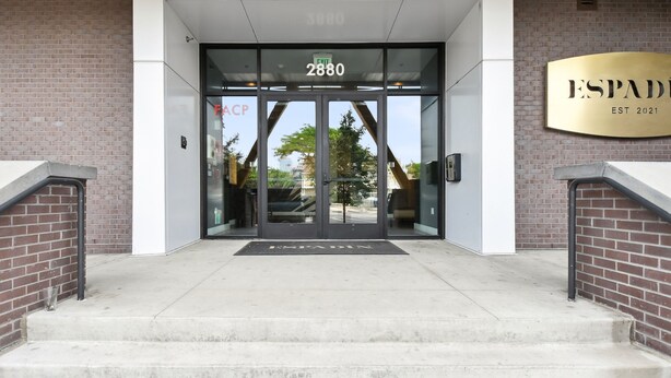 Entrada de un edificio con puertas de vidrio, un cartel que dice "ESPADIN EST 2021" y el número "2880" sobre las puertas.