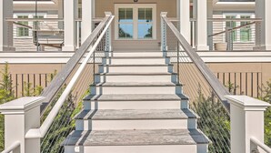 A staircase with a metal railing leading to a balcony with a view of a building. - 2410 The Bent Twig (Seabrook Island)