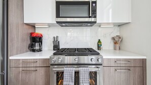 Una cocina equipada con microondas, estufa, horno y cafetera.