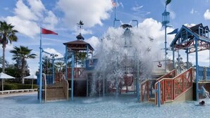 A water park with a central water feature, multiple slides, and a covered area with a red flag. - 2758bd · Dazzling 5BR Villa in Storey Lake With Pool & Spa (Kissimmee)