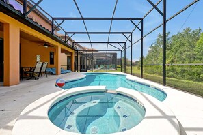 A swimming pool with a hot tub, a covered patio area, and a view of a residential building. - 2616 Tranquility, Kissimmee, 6 BED (Kissimmee)